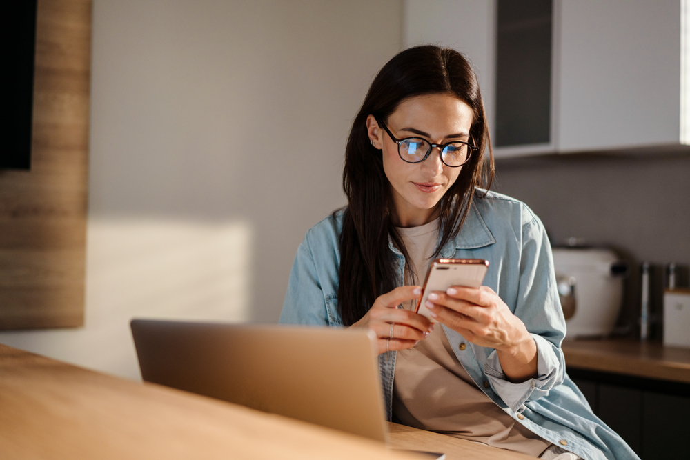 Young woman sat on her sofa at home whilst running an IMEI blacklist check on her Android device.