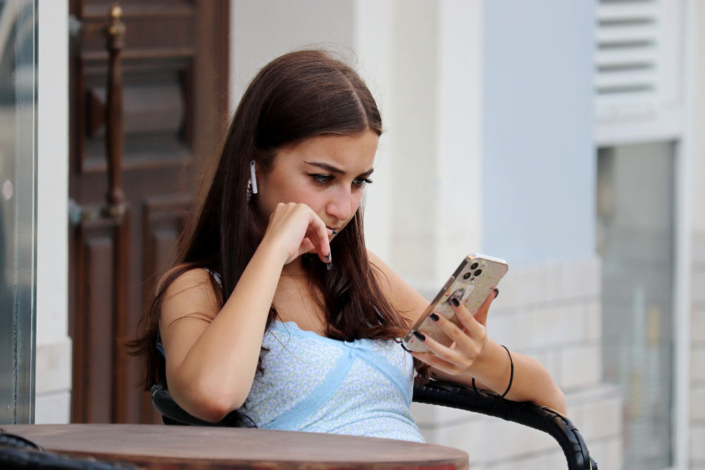 Young brunette checking her phone for an IMEI carrier check online.