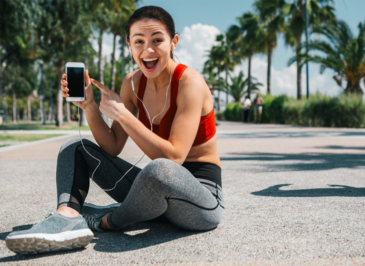 Athletic woman sat on the ground holding her GCI unlock phone device.