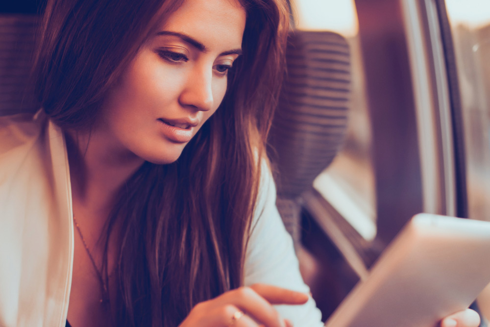 Attractive Asian woman finding out how to unlock an iPad online with Mobile Unlocked services.