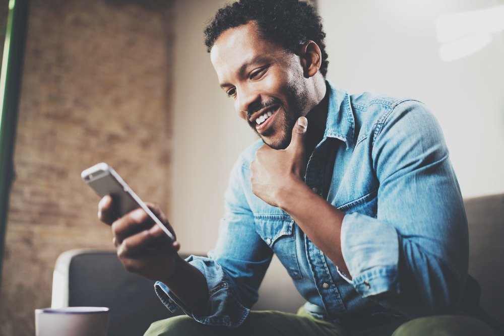 African American man who is smiling with an iPhone 11 Pro Max unlock.