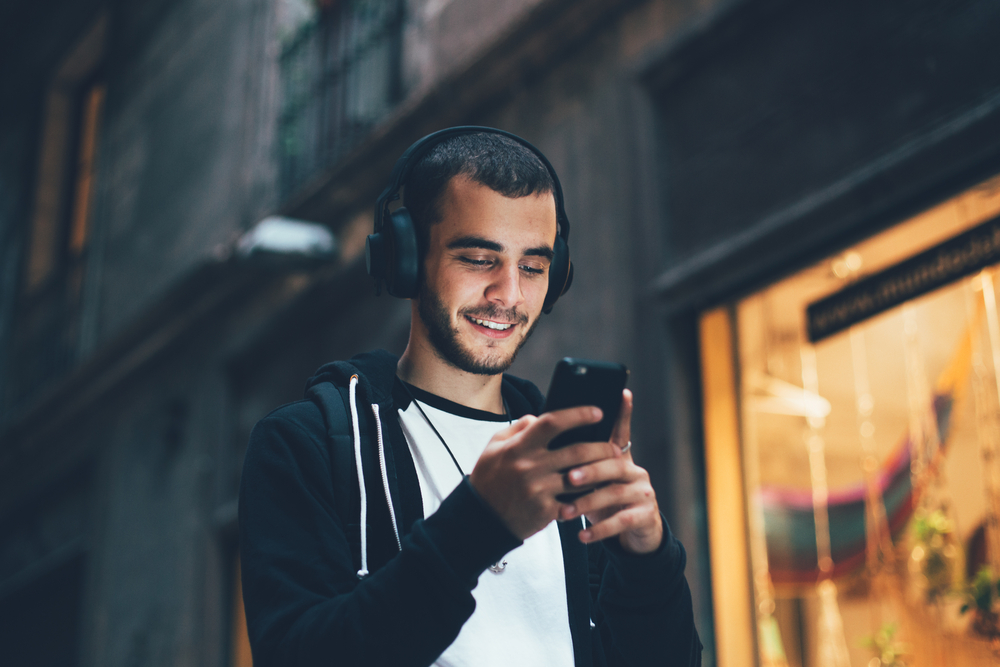 Joven usando audífonos mientras realiza una verificación de reemplazo de dispositivo en línea.