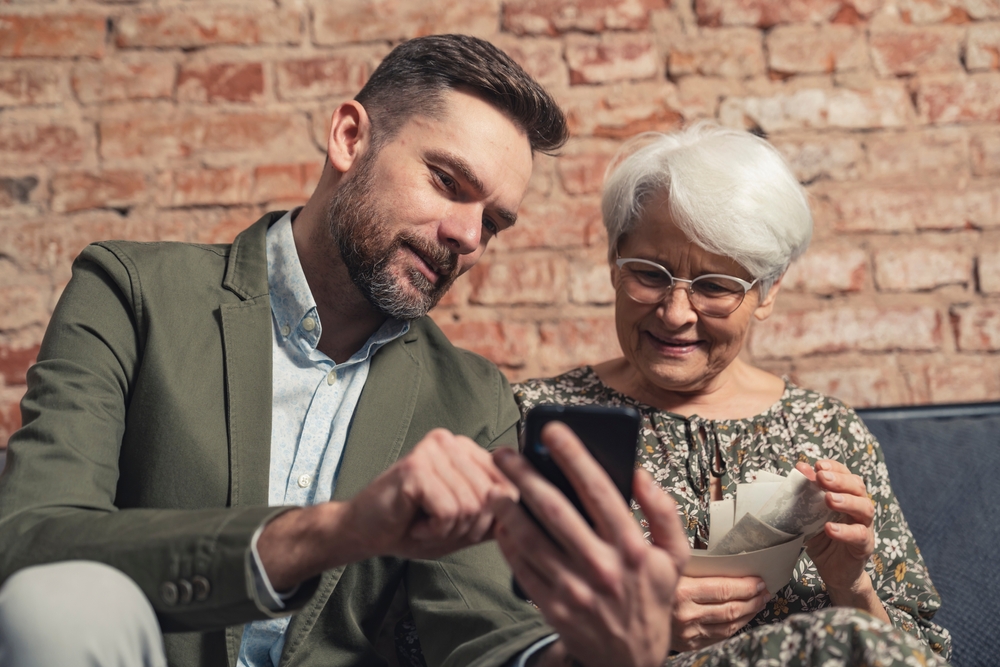 Son showing his mother a Sprint status check on her mobile device.