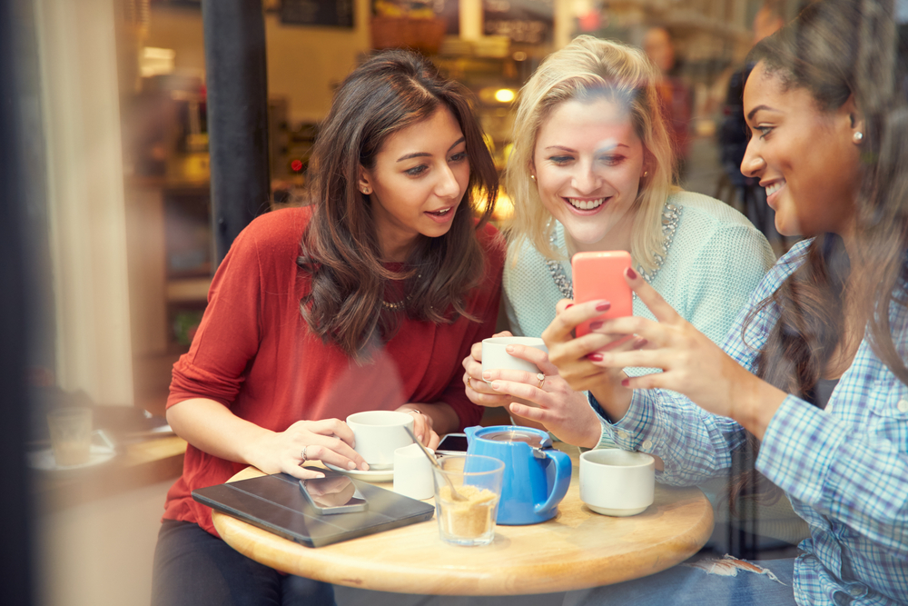 Three girls checking how to unlock an iPhone 6 online with Mobile Unlocked.