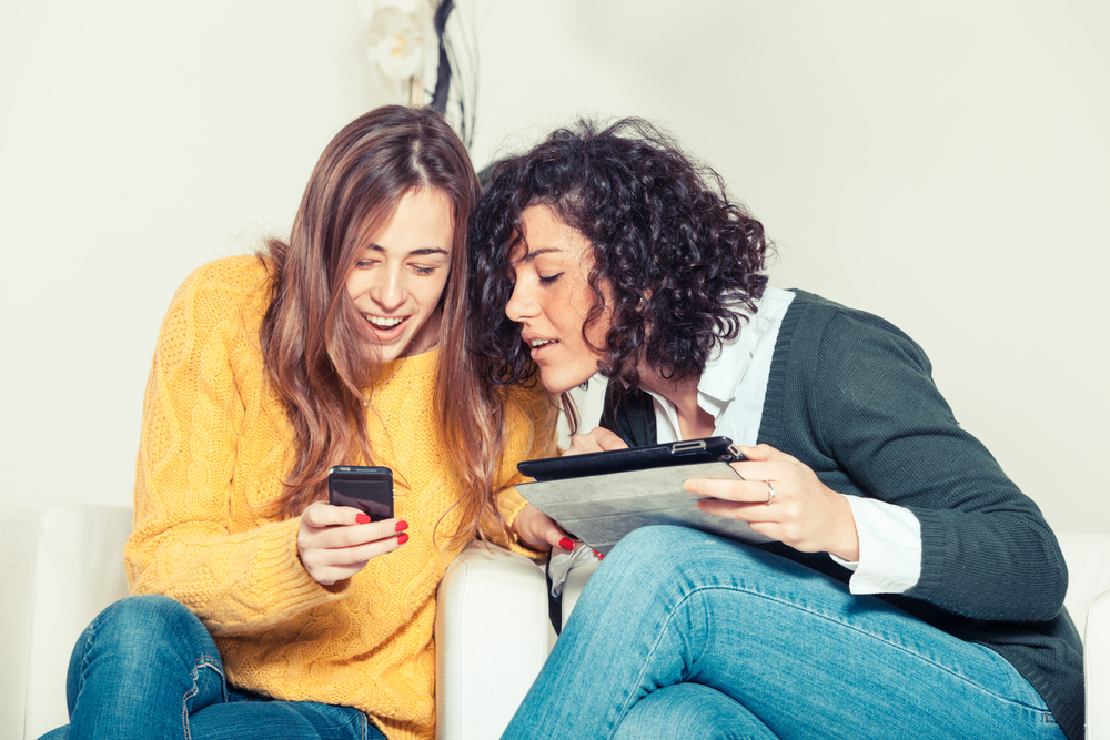 Two woman looking at an unlocked iPhone 7S mobile device.