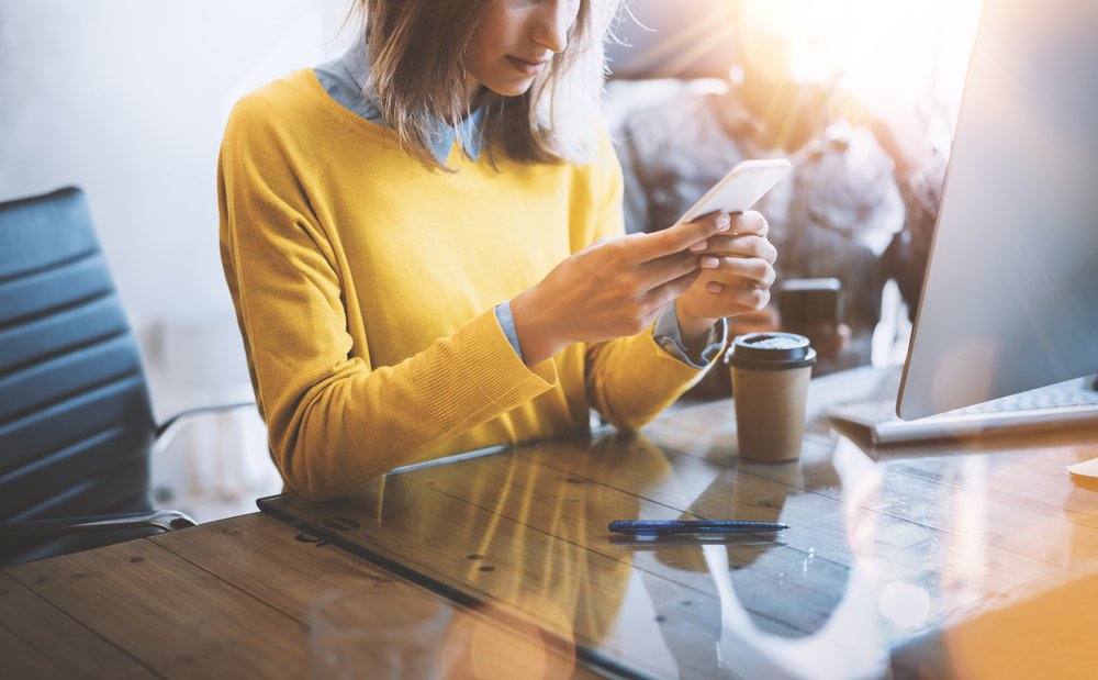 Young blonde woman unlocking her iPhone Xr online with Mobile Unlocked.