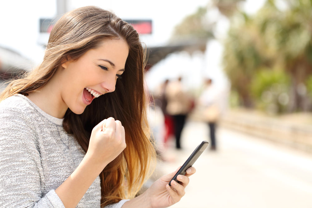 Young woman celebrating that she has a unlocked her Vodafone phone online.